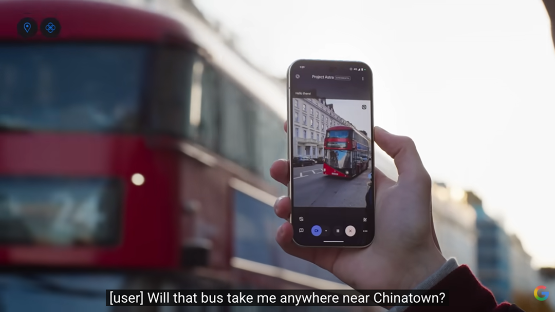A hand holds a smartphone running Project Astra, camera pointed at a red London double-decker bus on a city street. A subtitle reads "Will that bus take me anywhere near Chinatown?"